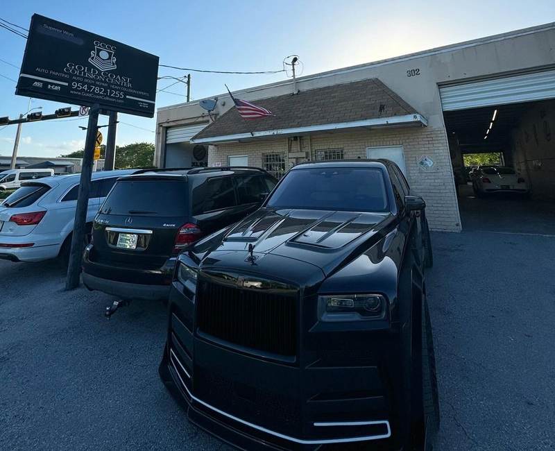 Gold Coast Collision Center storefront in Pompano Beach with a Rolls-Royce Cullinan parked outside